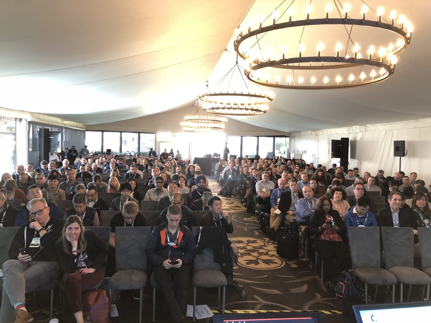 A full room of delegates in the summit marquee, rows of grey chairs, seats at the front marked reserved for speakers