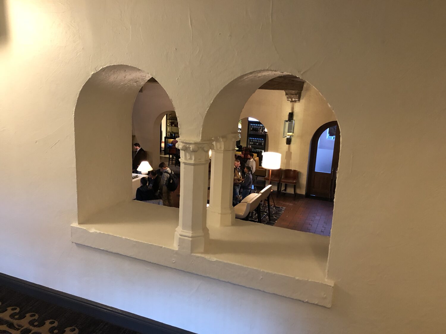 Delegates in the Inn lobby seen through the plastered arches of the colonnade