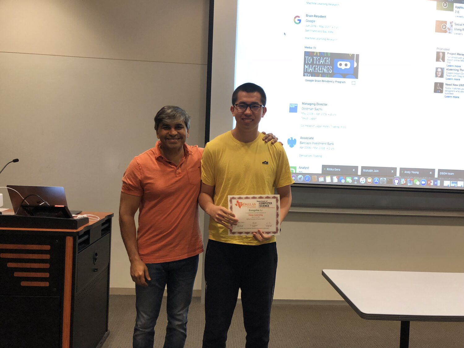 A delegate holds the Deep Learning certificate at the front of the teaching room