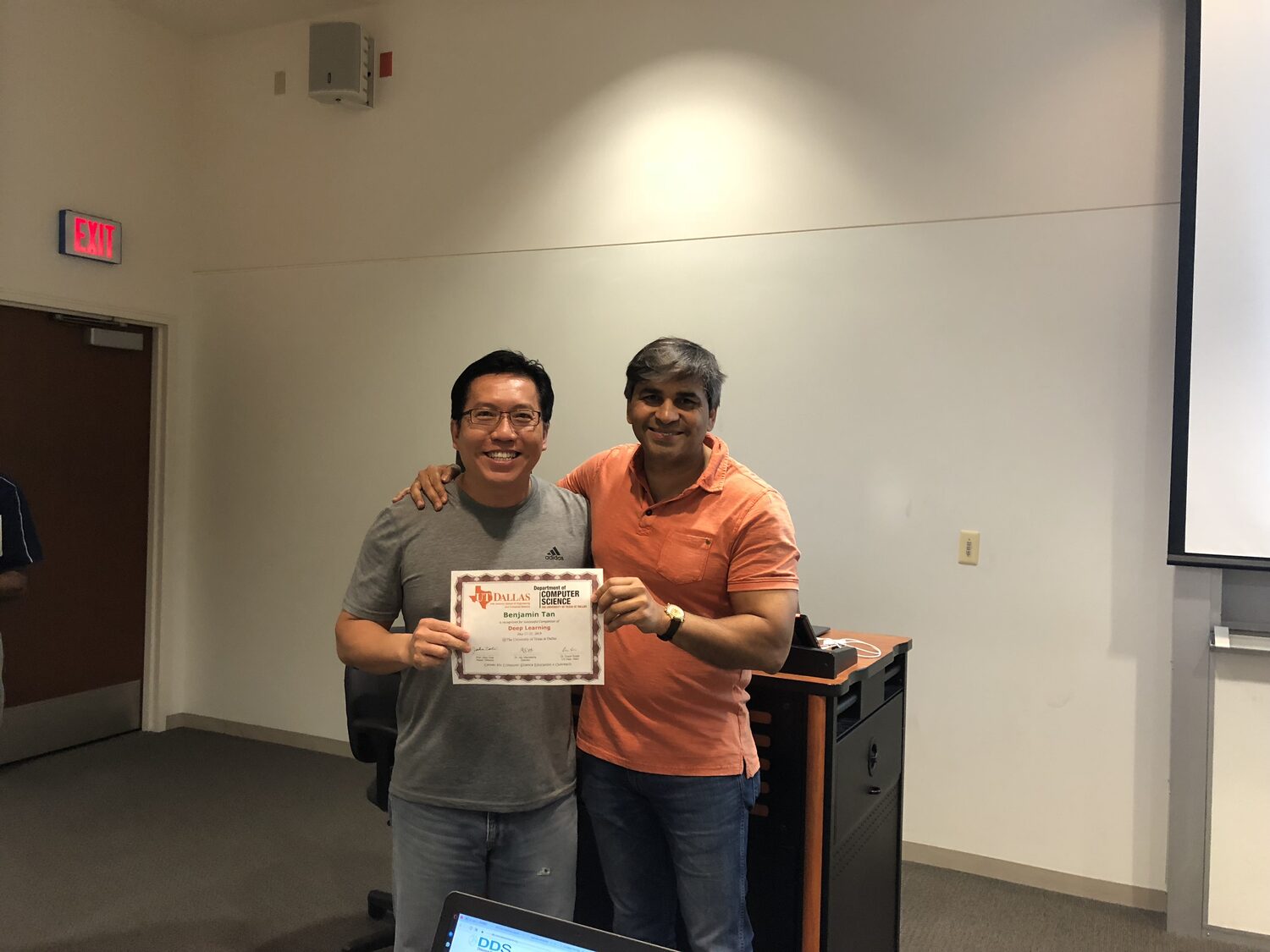 Certificate handover in the teaching room, projector screen behind