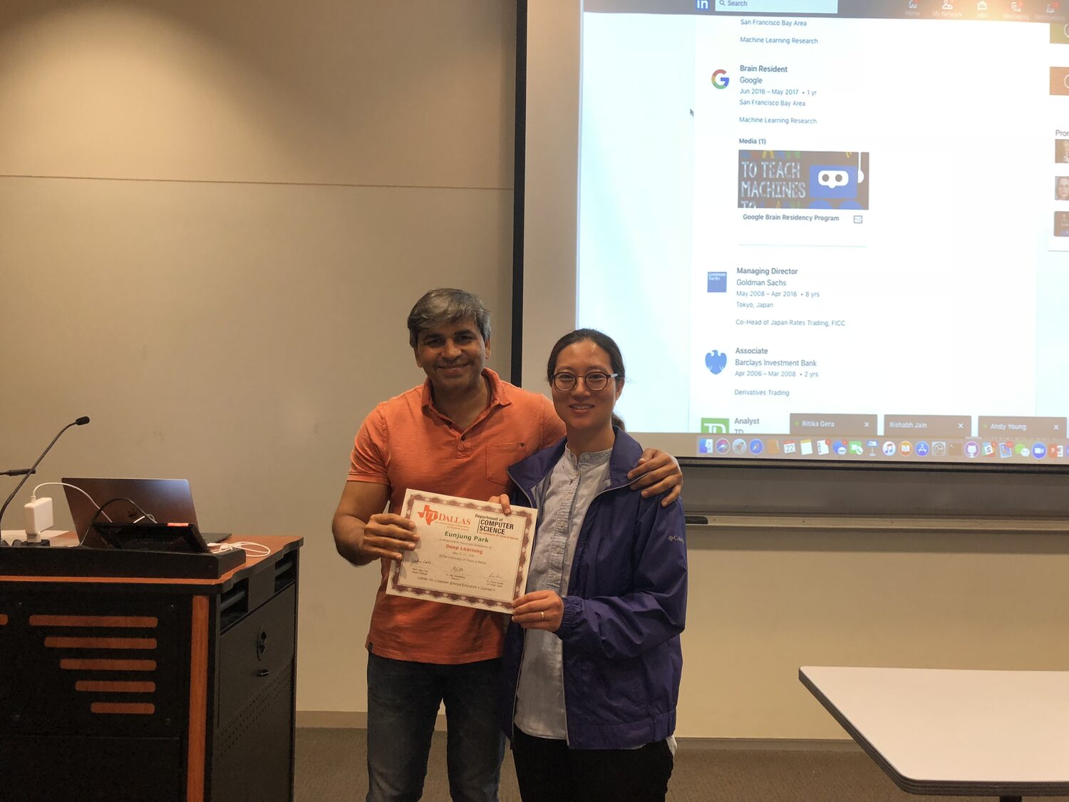 A delegate holds the certificate at the front of the classroom