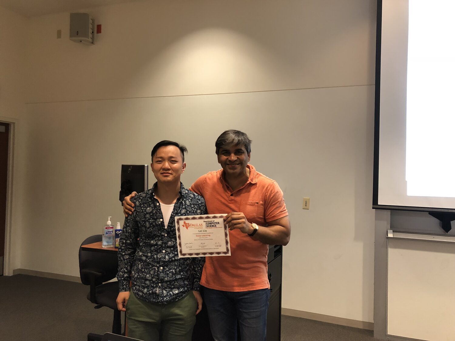 A delegate holds the certificate beside the teaching station