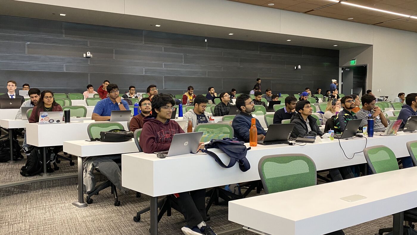 The lecture hall part-way through the week, every bench taken and a laptop open at almost every seat.