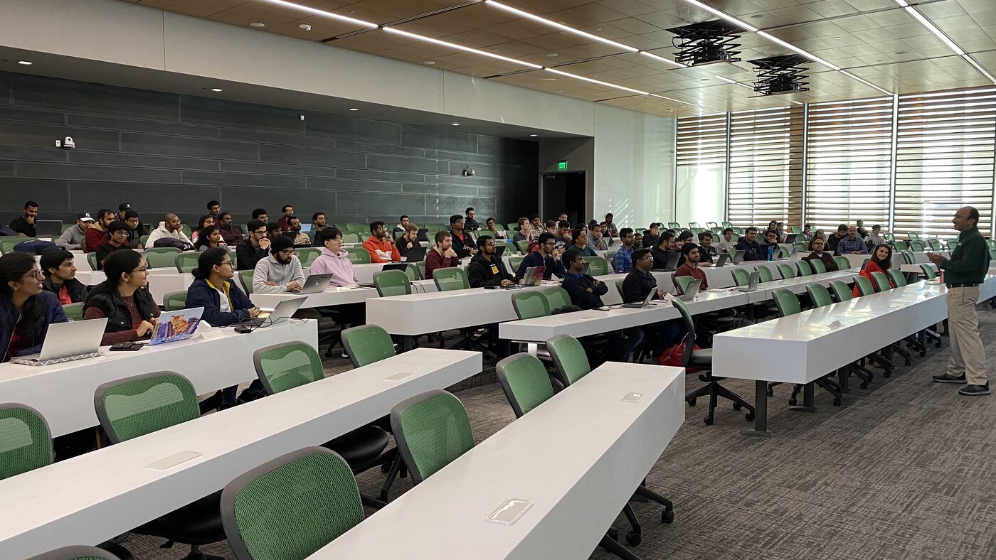 The hall from the front, benches curving back in rows, the cohort at work.