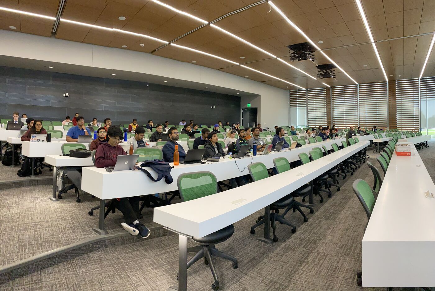The lecture hall during a session, participants at the benches with laptops open.