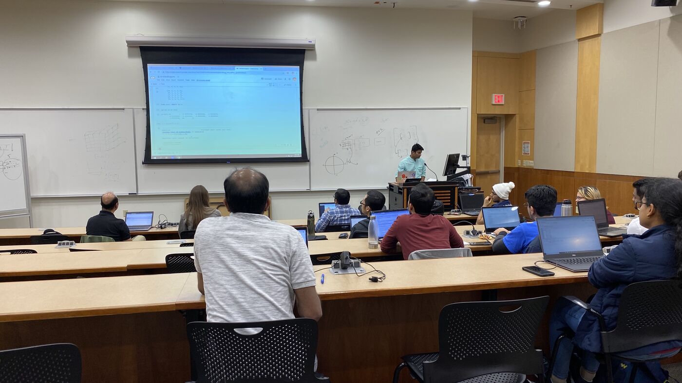 The lecture hall during a session, participants at the benches with laptops open.