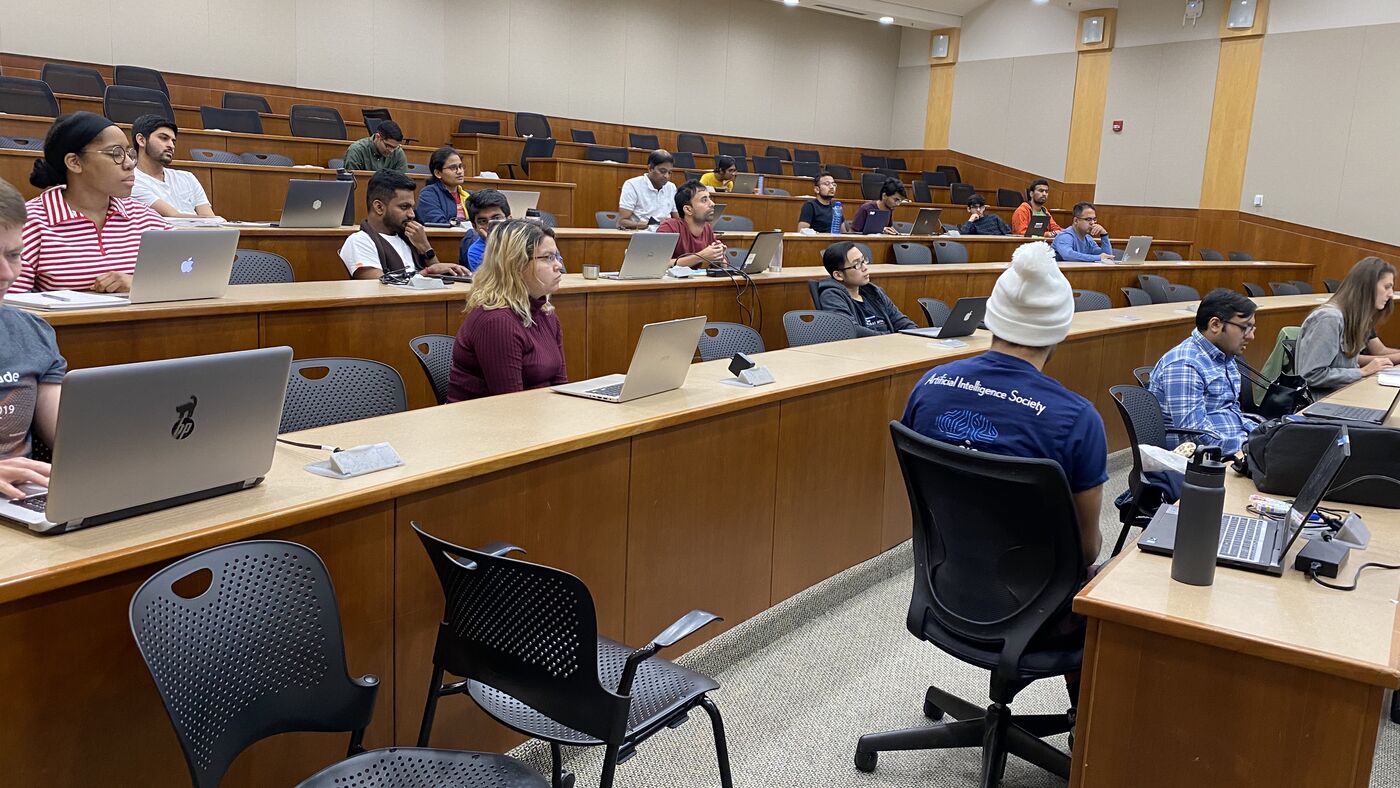 The lecture hall during a session, participants at the benches with laptops open.