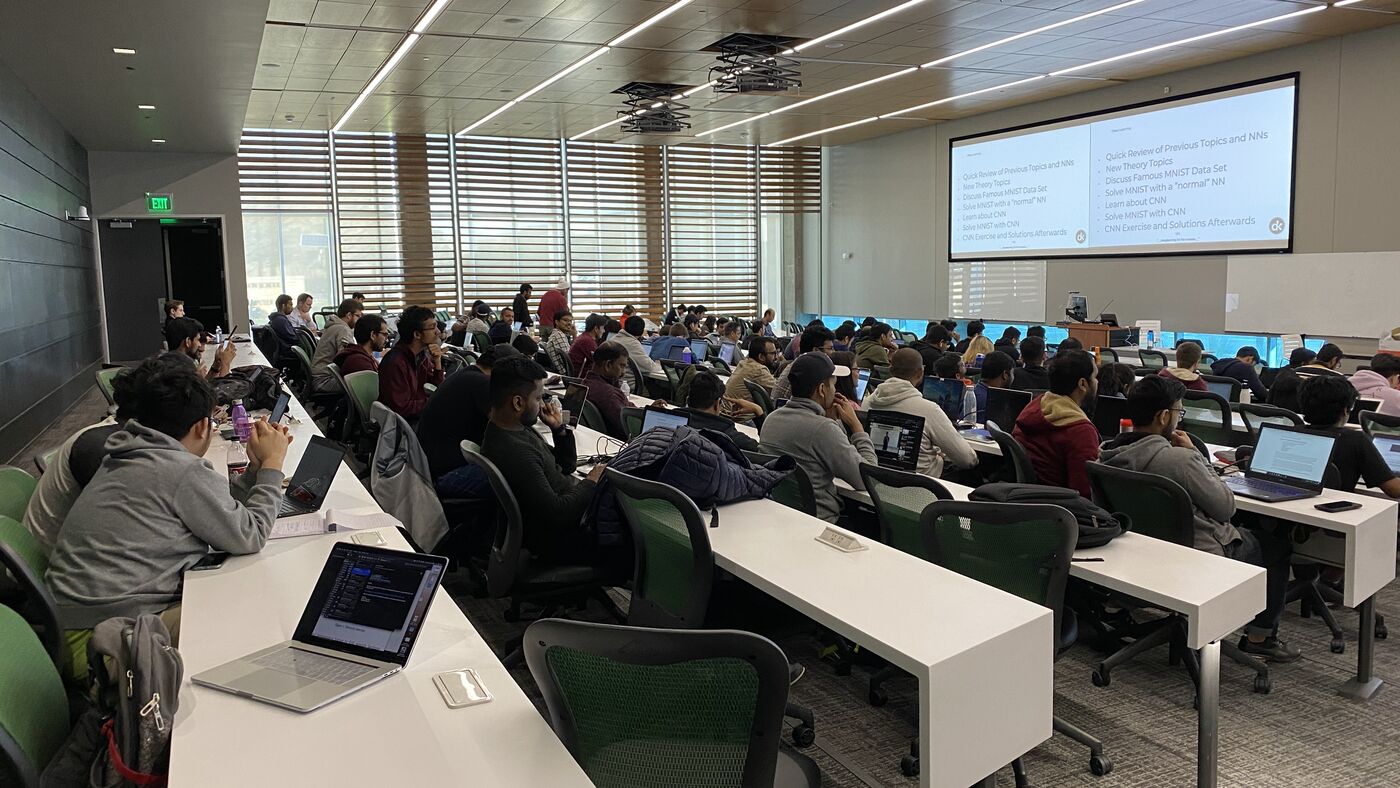 The lecture hall during a session, participants at the benches with laptops open.