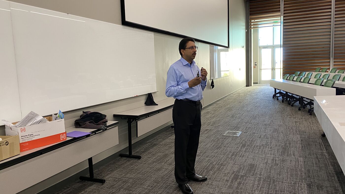 An instructor presenting to the room, whiteboard behind.