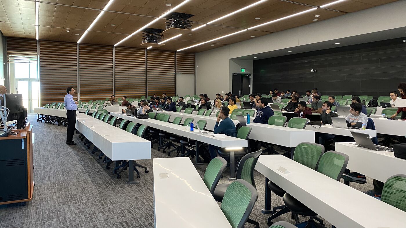 The lecture hall during a session, participants at the benches with laptops open.