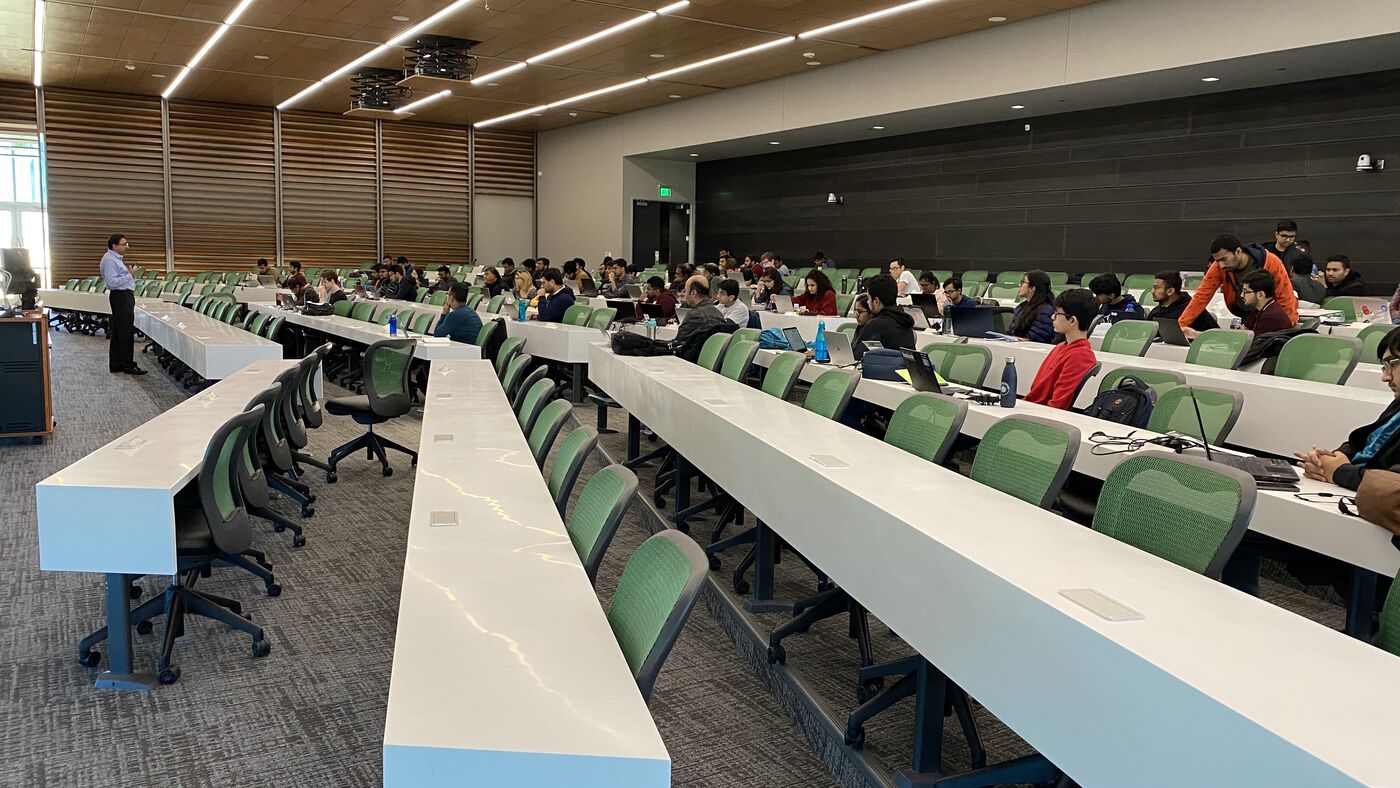 The lecture hall during a session, participants at the benches with laptops open.