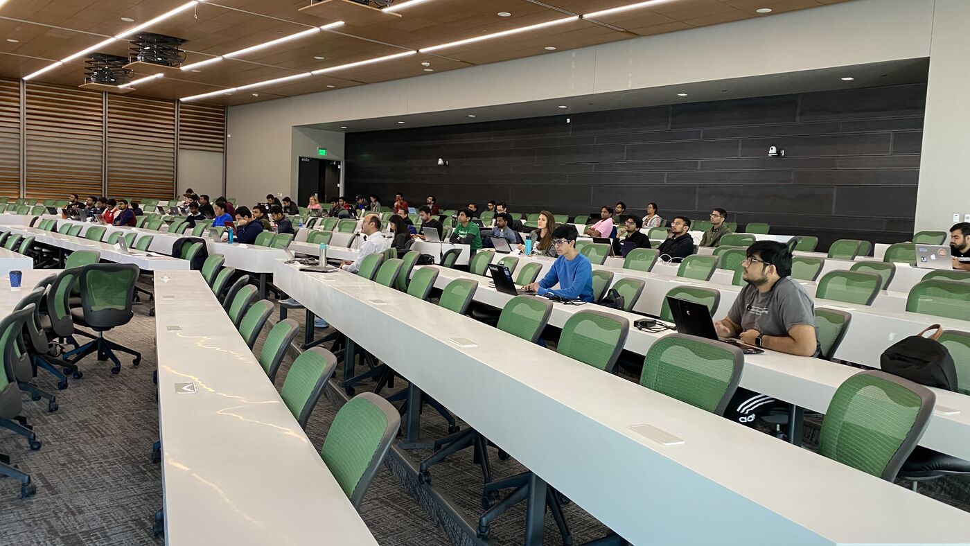 The lecture hall during a session, participants at the benches with laptops open.