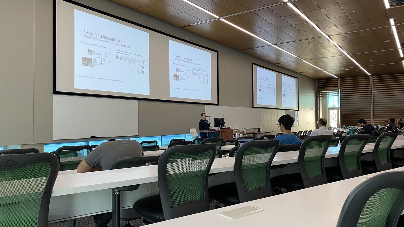 The lecture hall during a session, participants at the benches with laptops open.