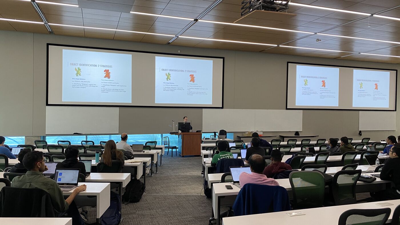 The lecture hall during a session, participants at the benches with laptops open.