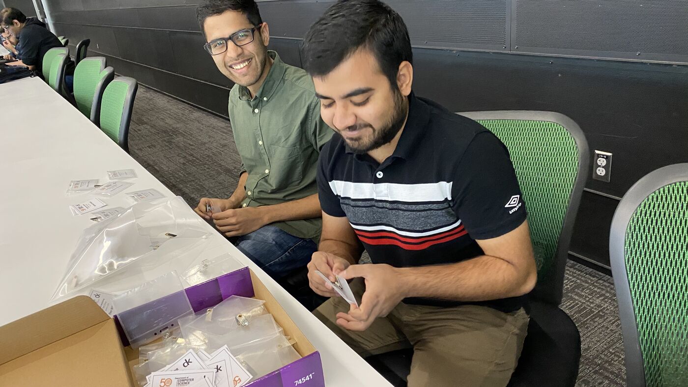 Two participants at a bench with the workshop kit open in front of them.