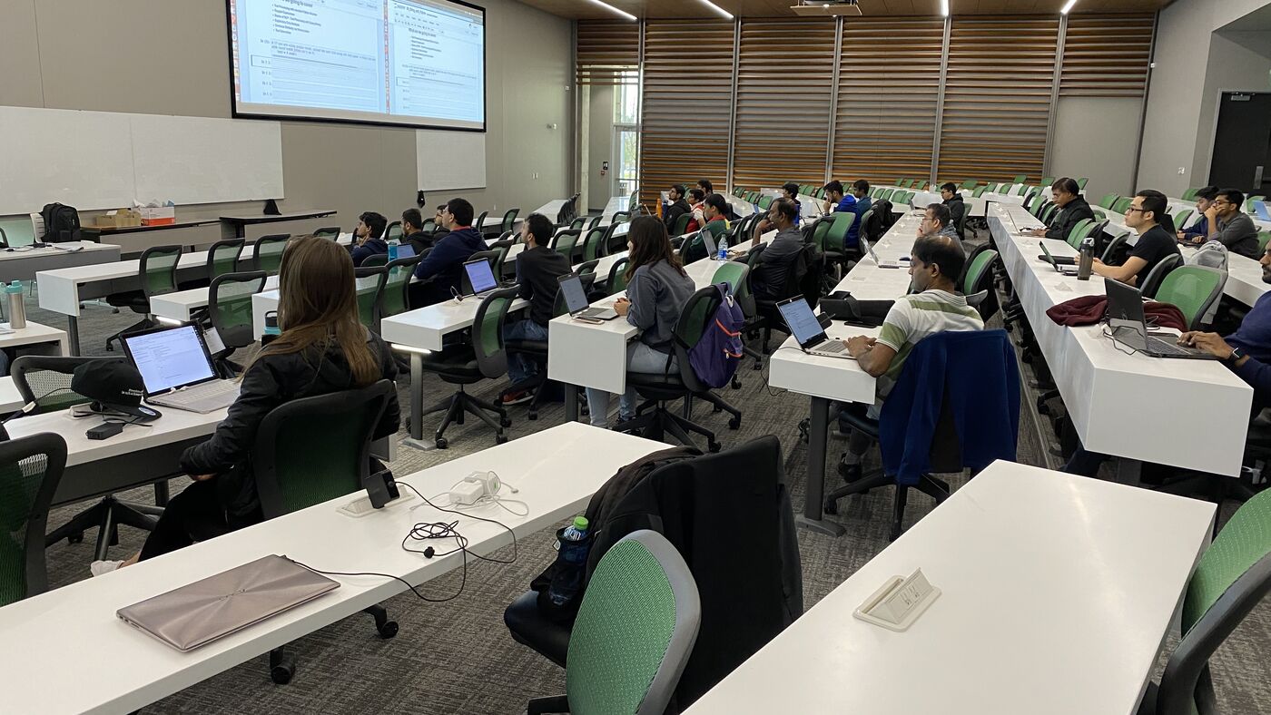 The lecture hall during a session, participants at the benches with laptops open.