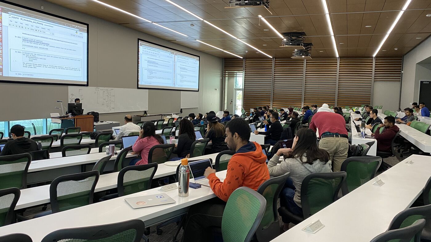 The lecture hall during a session, participants at the benches with laptops open.