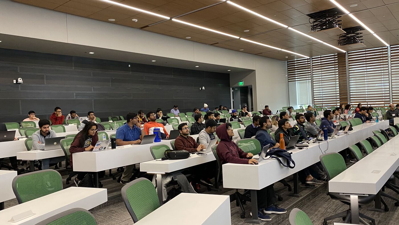 The lecture hall during a session, participants at the benches with laptops open.