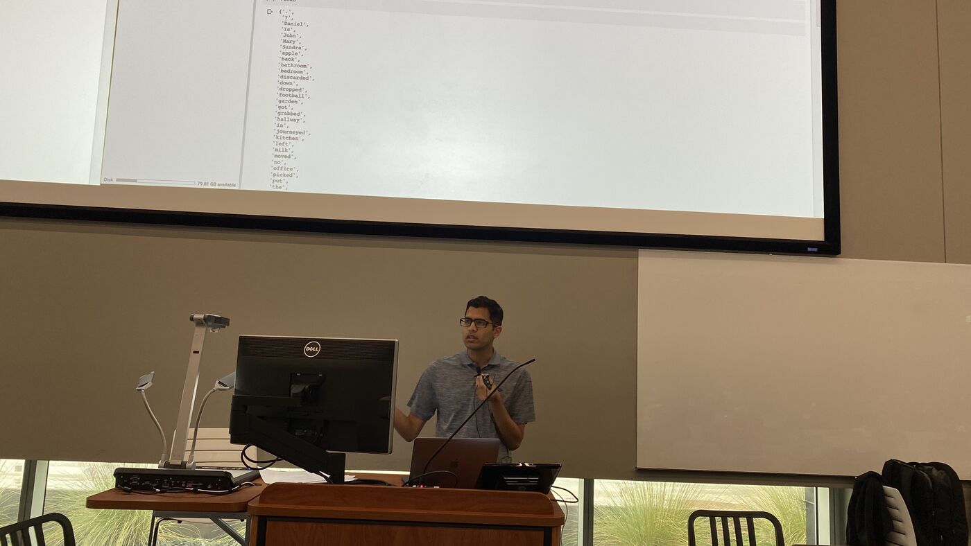 An instructor at the lectern with a laptop open in front of them.